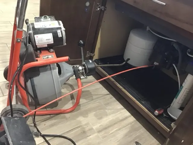 A Trident plumber clearing a kitchen drain in Phoenix