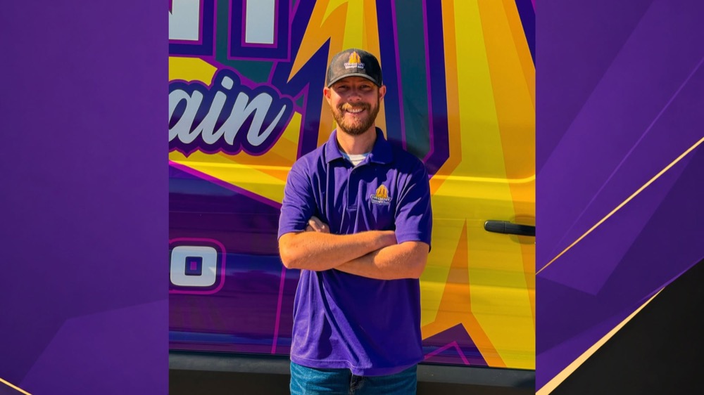 A Trident Plumbing & Drain team member in front of a branded company van