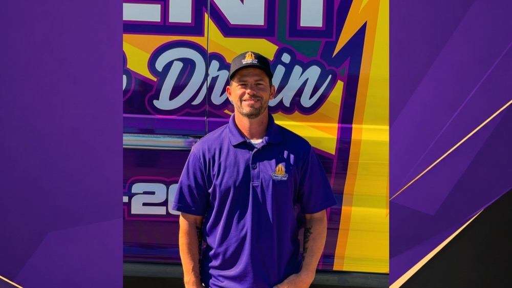 A Trident Plumbing & Drain team member in front of a branded company van