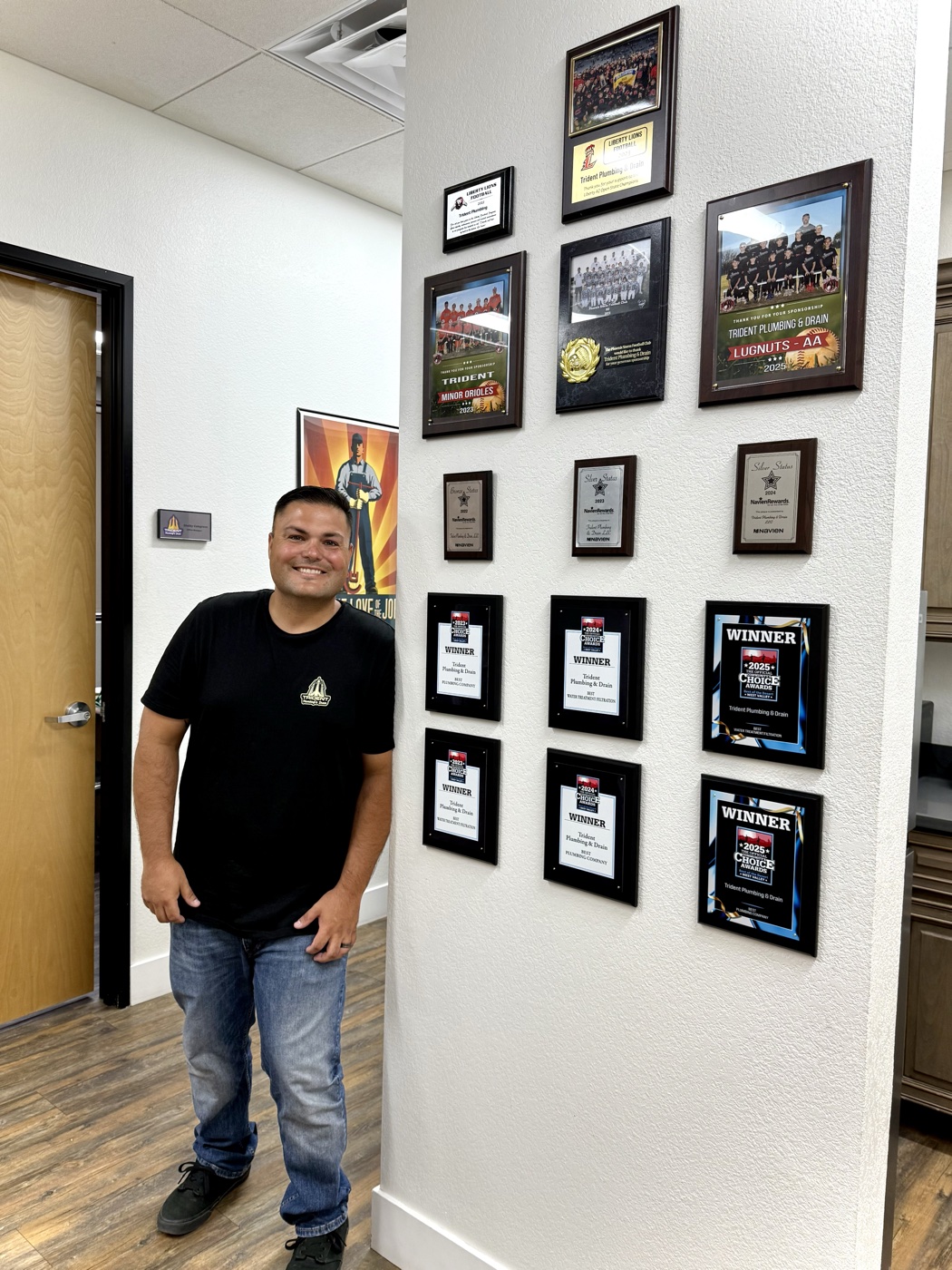 Jared at Trident Plumbing's award wall — Community Choice Award and Best of the Desert Winner